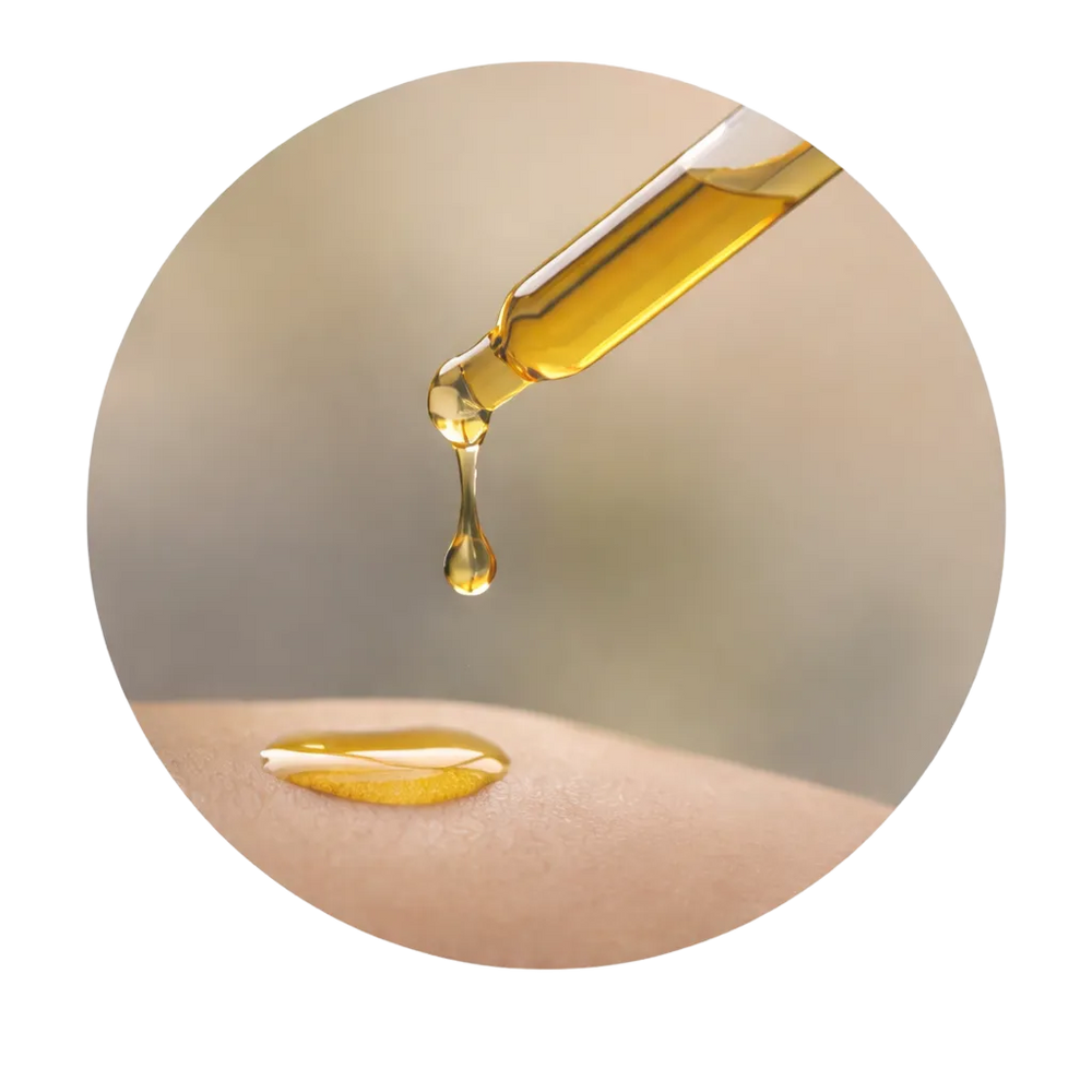 Pipette lässt goldenen Tropfen Öl auf Hautoberfläche fallen, sanfter, pflegender Moment.